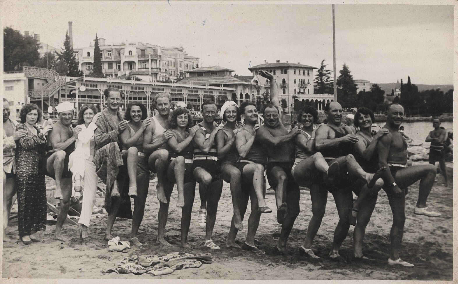 a photo taken in the early 1900s of a conga line assembled by beachgoers at an oceanside resort